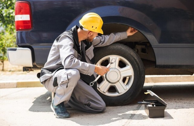 Mechanic performing car maintenance by checking tire pressure